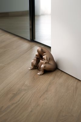 Brauner Alessi Dede Türstopper aus Metall, skulpturales Design, hält Tür auf Holzboden offen.